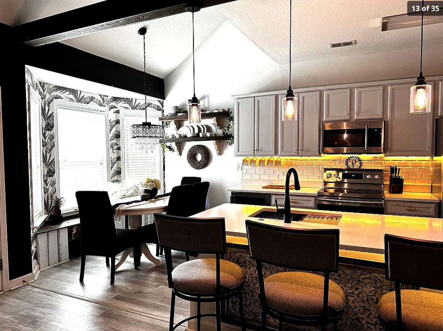 Kitchen island with bar stools, pendants, and dining nook